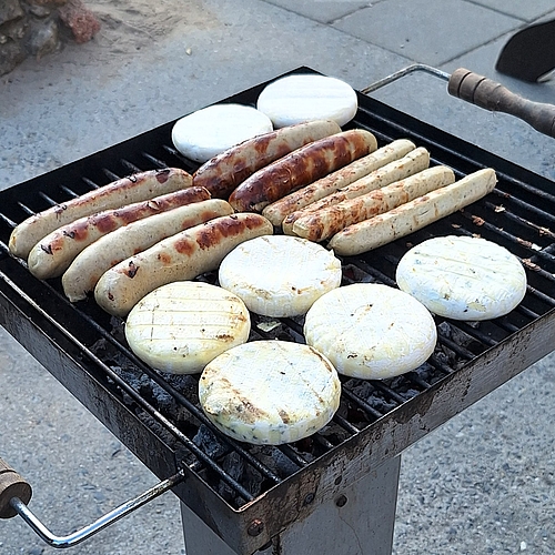  Auf einem Grill brutzeln mehrere Bratwürste und Grillkäse.
