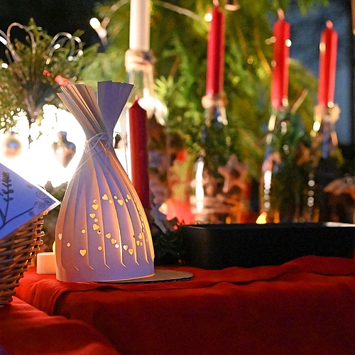 Ein stimmungsvoll beleuchteter Tisch mit Adventsdeko, Kerzen und kleinen Geschenkideen.